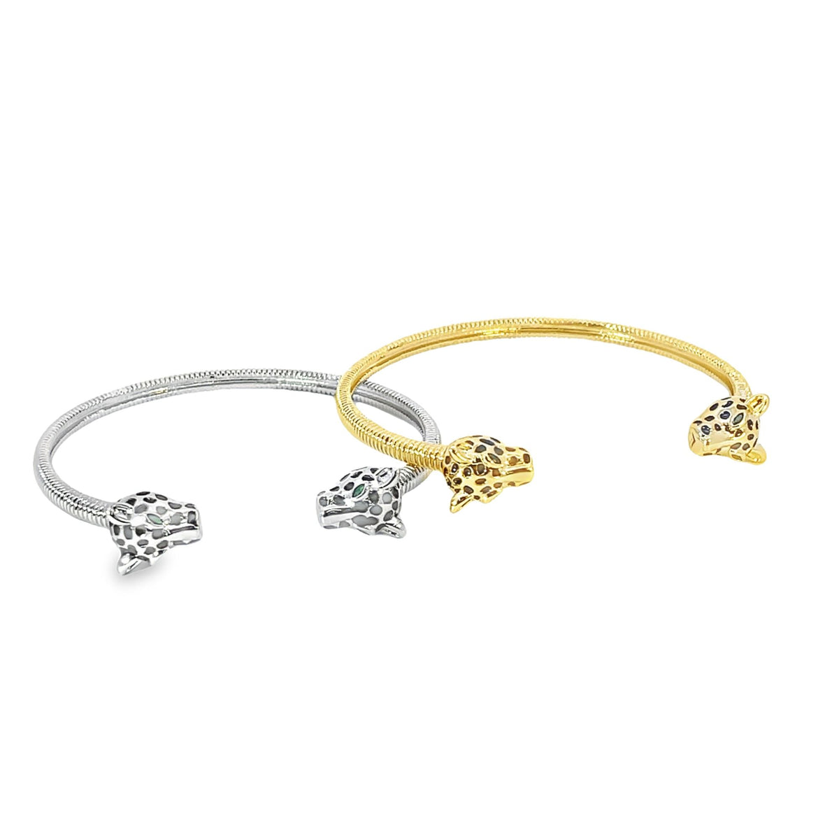 Two snake-like animalistic bangles, one silver and one gold with spotted leopard head accents, rest side by side on a plain white background.