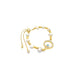 A gold adjustable bracelet features white freshwater pearls and a sparkling evil eye charm against a white background.