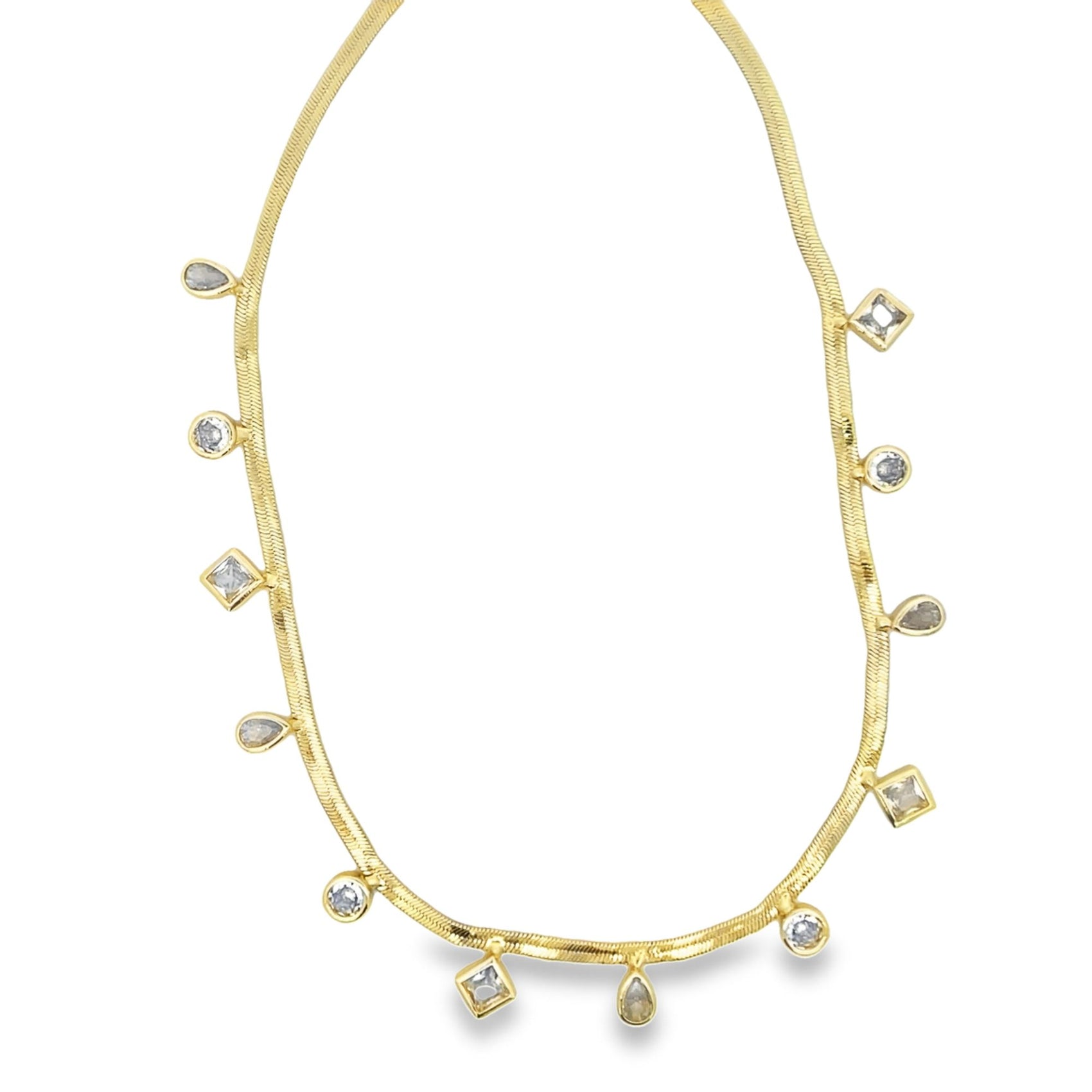 A delicate gold herringbone chain necklace drapes gracefully against a white background, featuring dangling charms in round, square, and teardrop shapes.