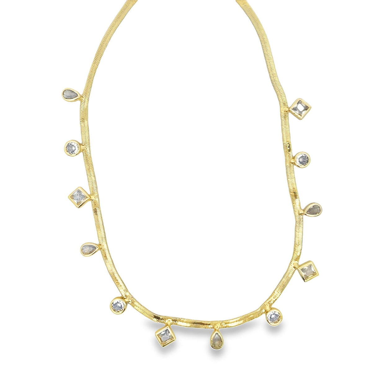 A delicate gold herringbone chain necklace drapes gracefully against a white background, featuring dangling charms in round, square, and teardrop shapes.