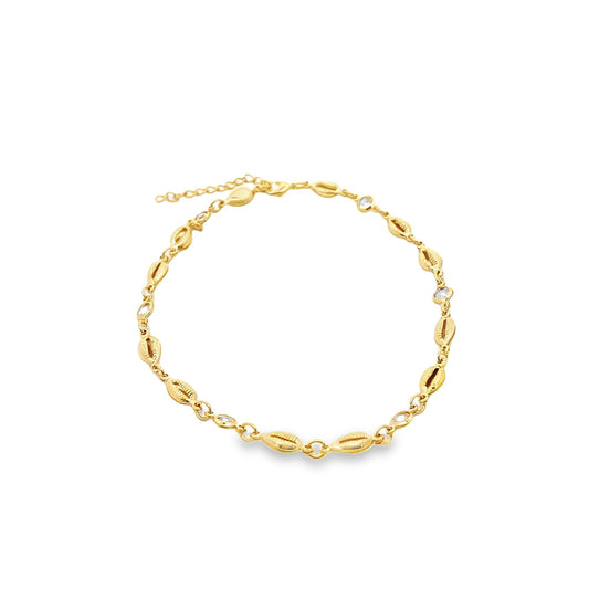 A gold chain bracelet features alternating metallic cowrie shells and small sparkling stones against a white background.