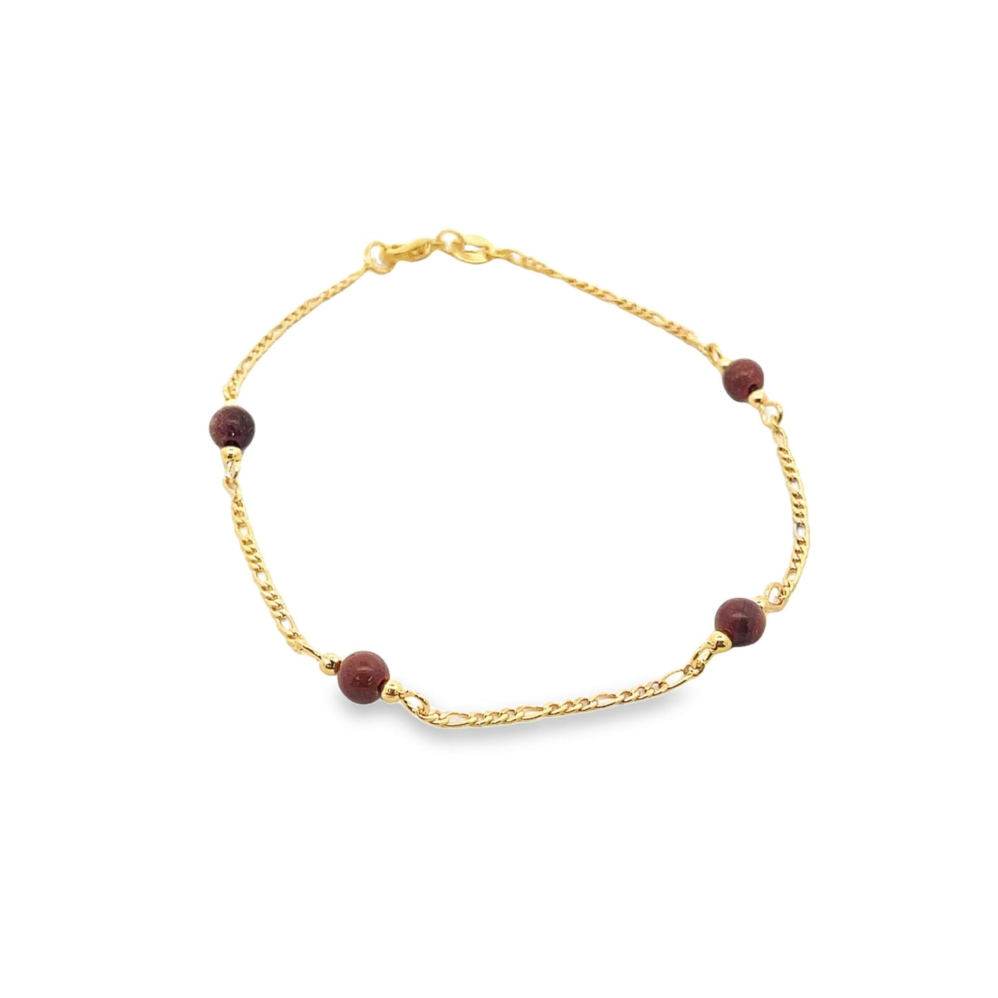 A delicate gold link bracelet features small, deep red gemstone beads evenly spaced along the chain against a white background.