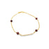 A delicate gold link bracelet features small, deep red gemstone beads evenly spaced along the chain against a white background.