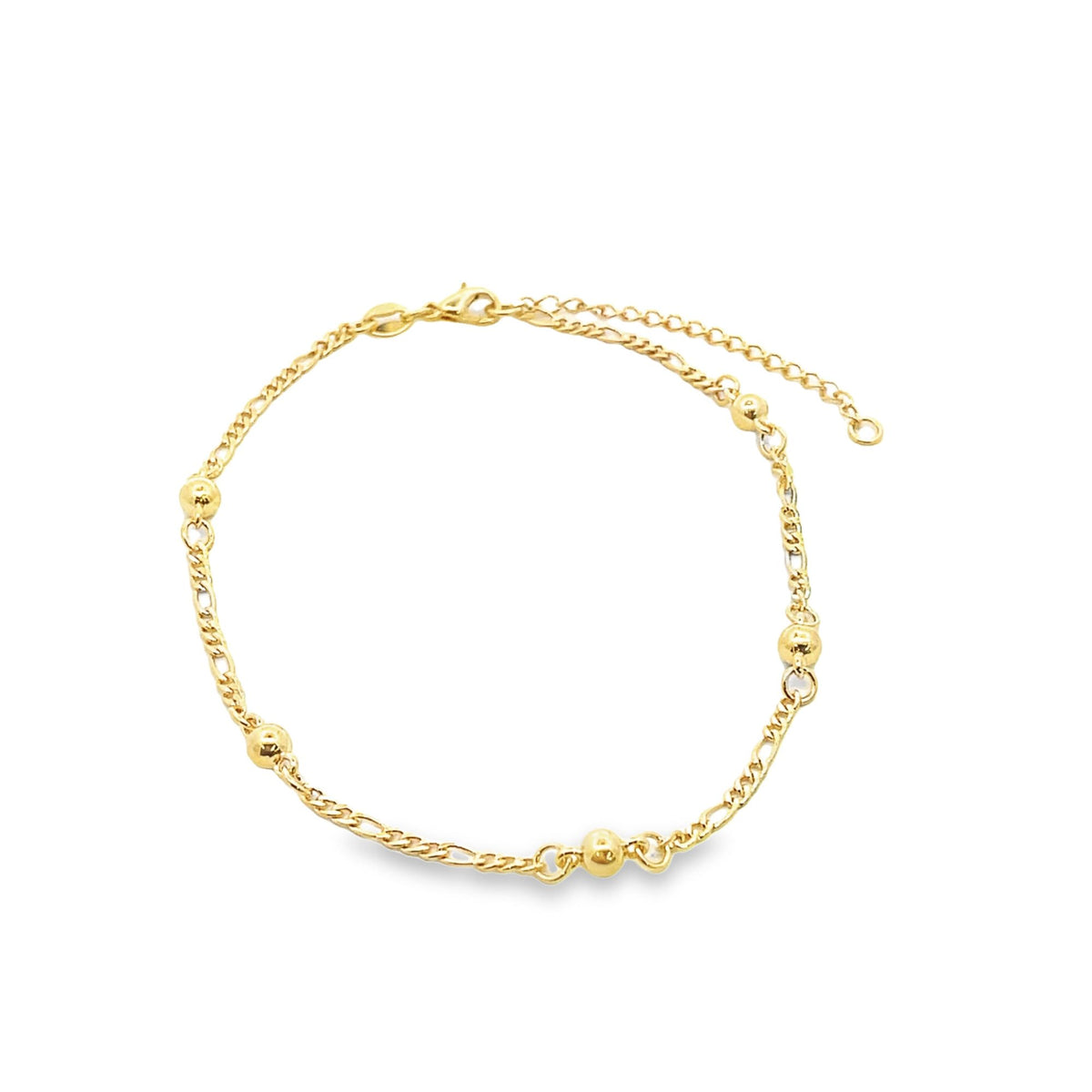 A delicate gold bead anklet curves against a clean white background, showcasing its alternating chain links and polished spherical charms.
