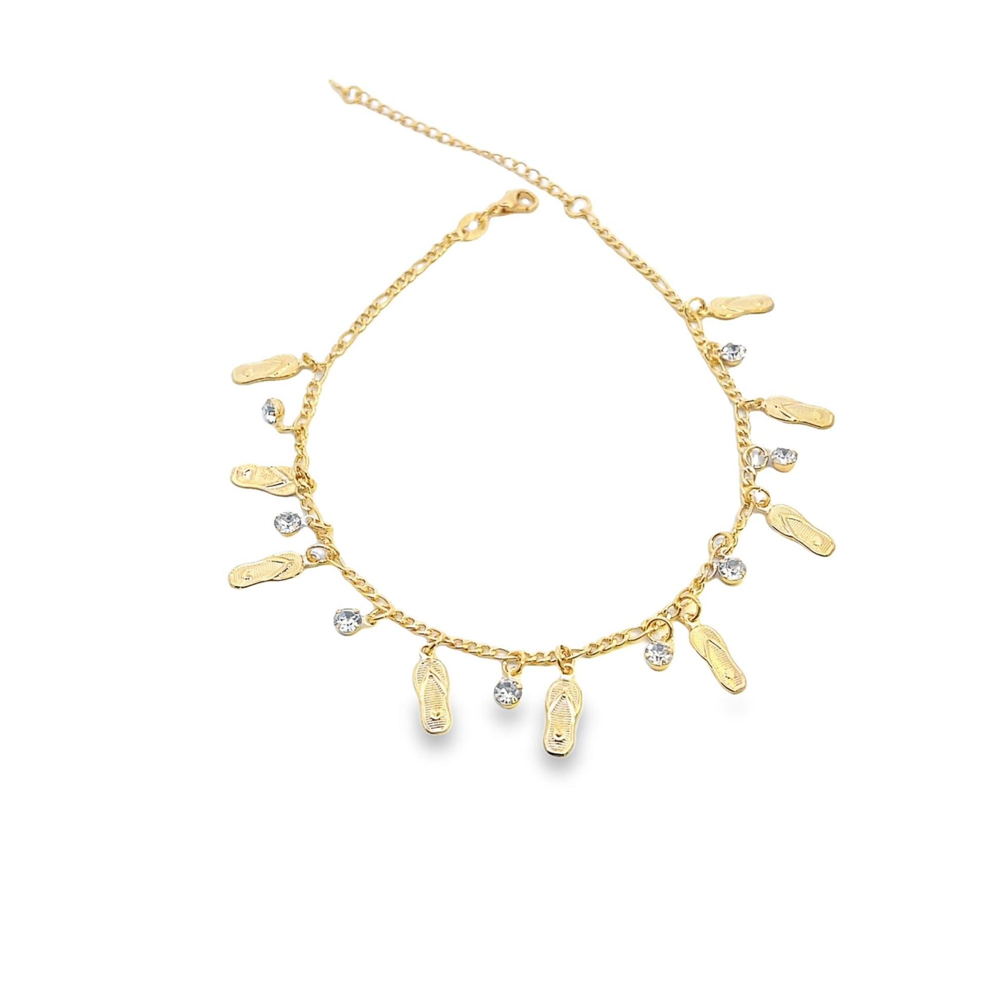 A delicate gold anklet features hanging flip-flop charms and sparkling rhinestone accents.