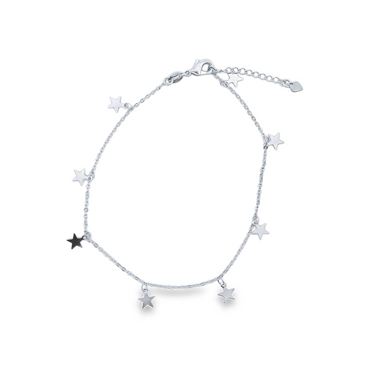 A delicate sterling silver star charm anklet rests in a circle against a white background.