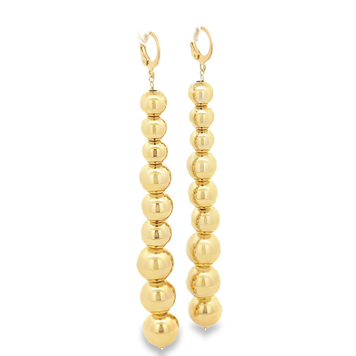 A pair of long, dangling gold bead earrings hangs vertically against a clean white background.