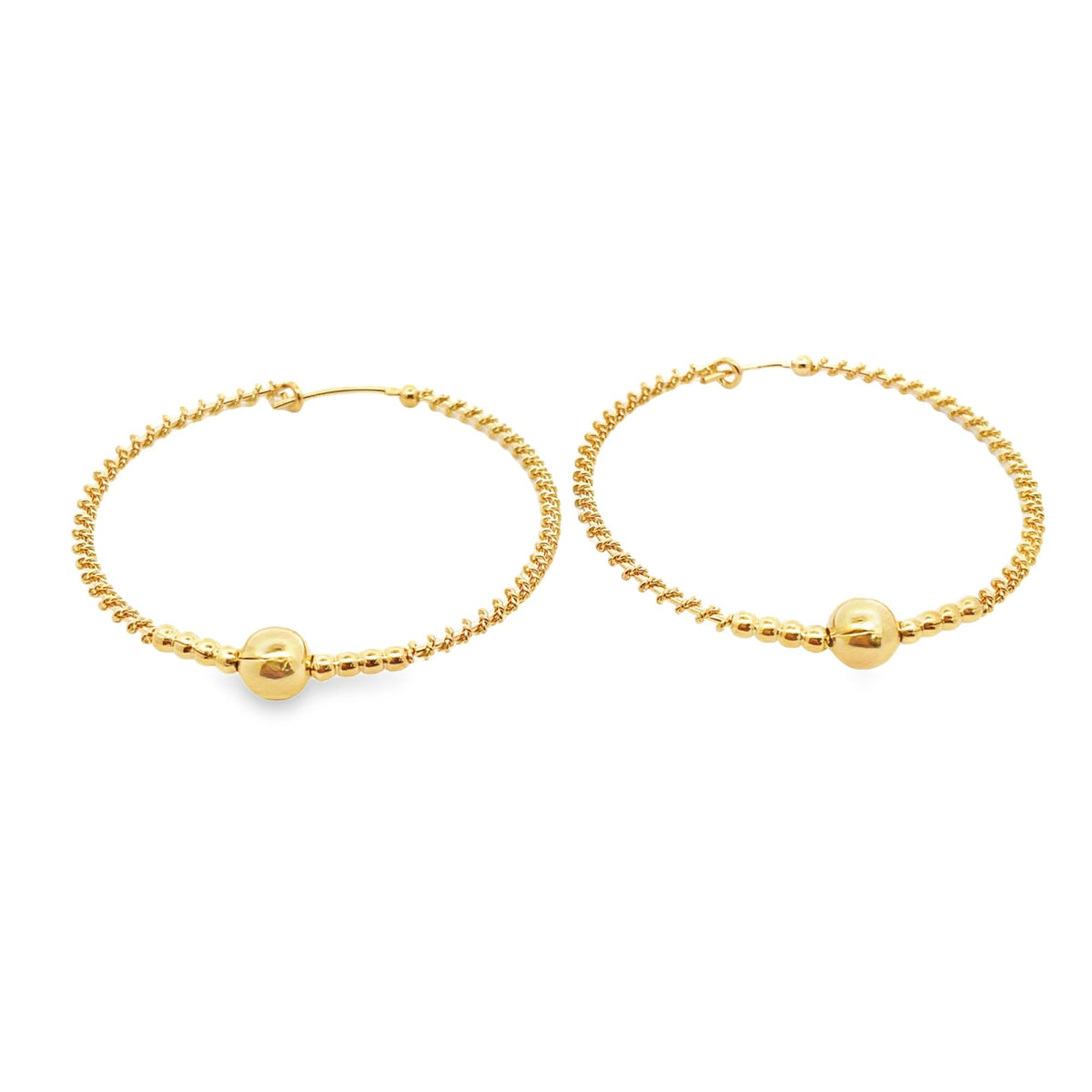 A pair of textured gold hoop earrings featuring a central polished ball rests on a clean white surface.