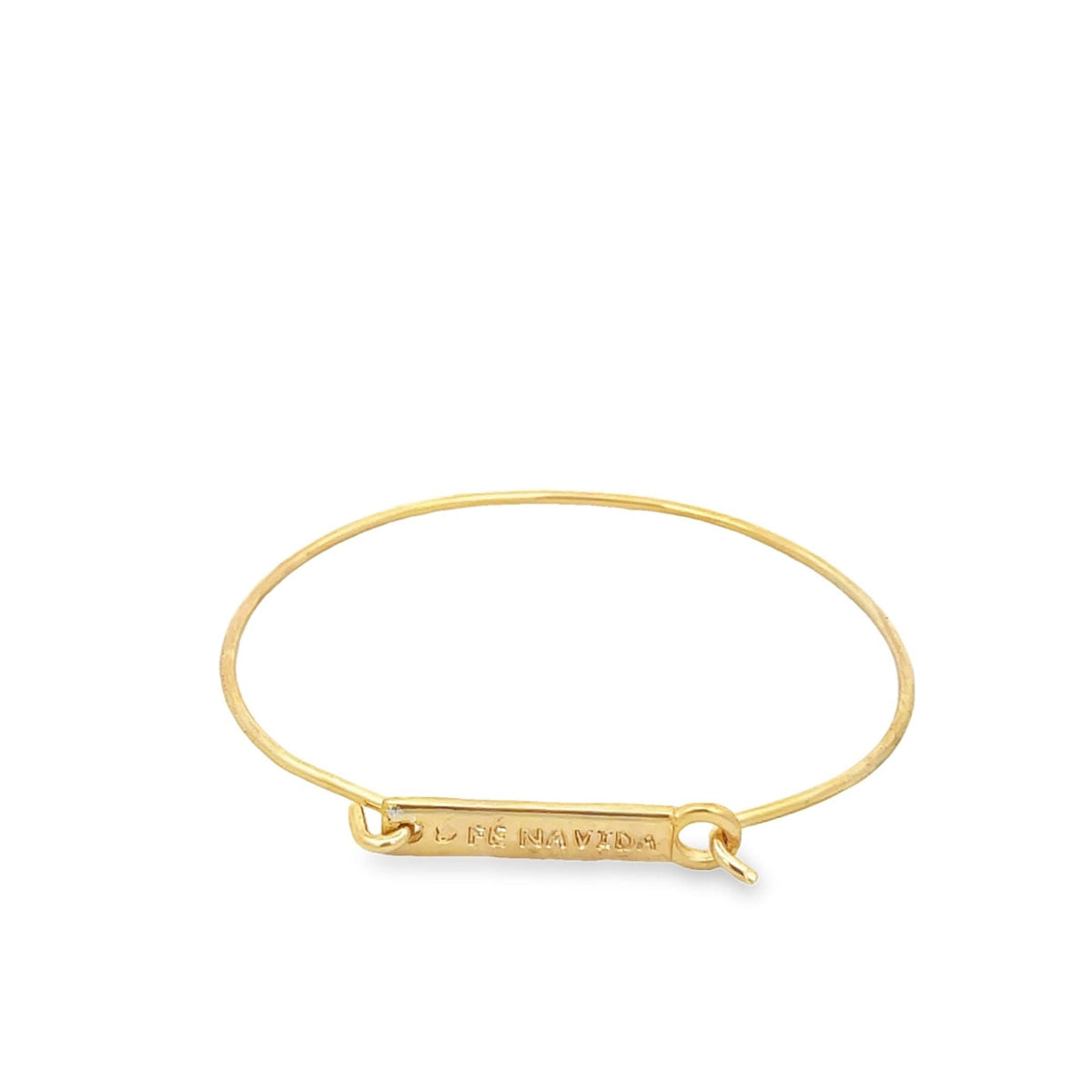 A minimalist gold wire bangle bracelet features an engraved rectangular bar charm displaying the phrase "FE NAVI DA."