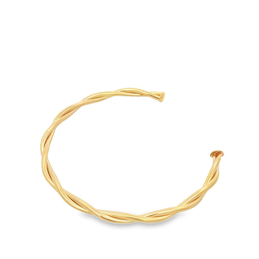 A gold twisted wire open cuff bracelet rests on a white background.