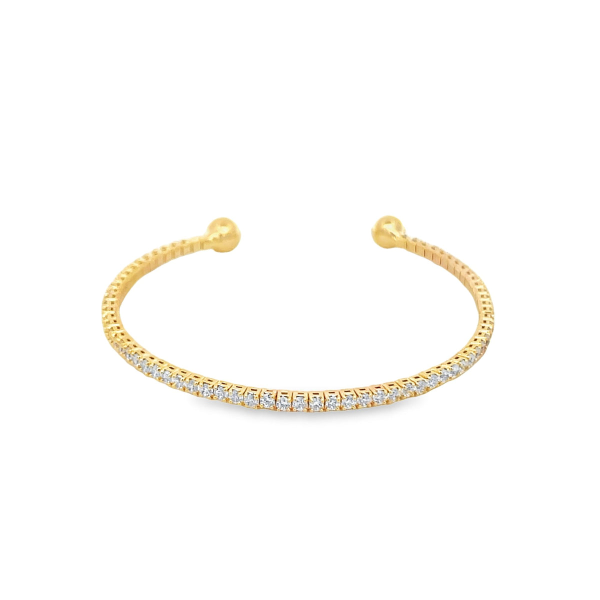 A delicate gold cuff bracelet sparkles with a continuous row of small diamonds and features rounded ball ends against a plain white background.