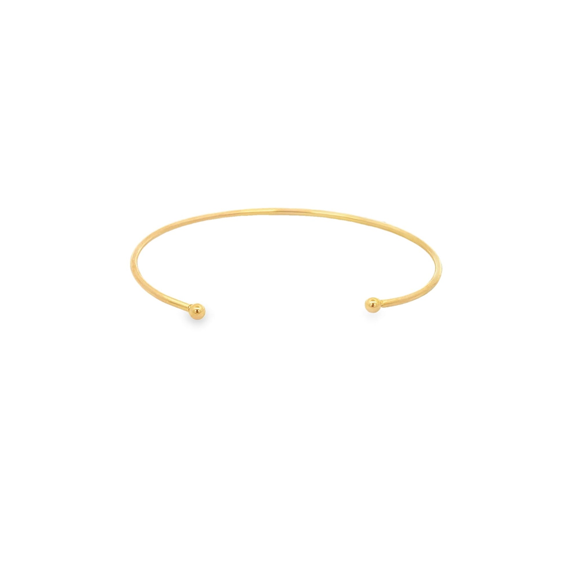 A minimalist gold cuff bracelet rests on a clean white background, showcasing its sleek open design with ball ends.