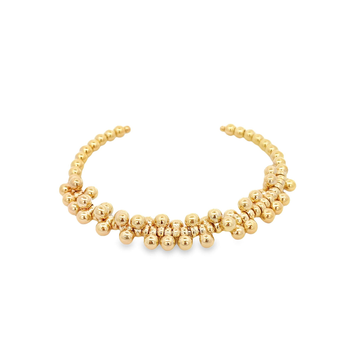A shiny gold beaded cuff bracelet rests on a white background.