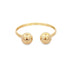A polished gold open-ended ring features two smooth spheres facing each other on a clean white background.