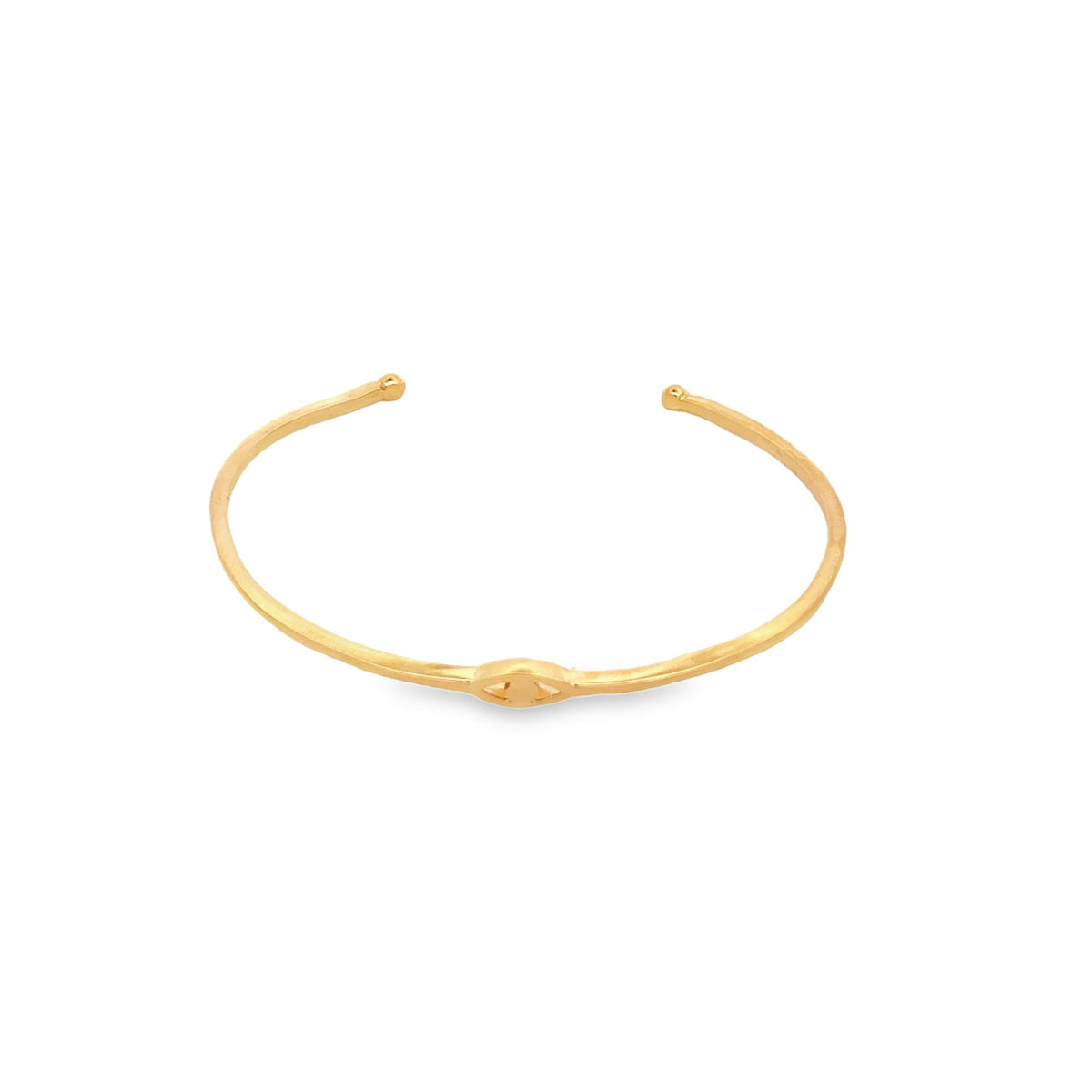 A sleek gold cuff bracelet featuring an evil eye motif rests isolated on a plain white background.