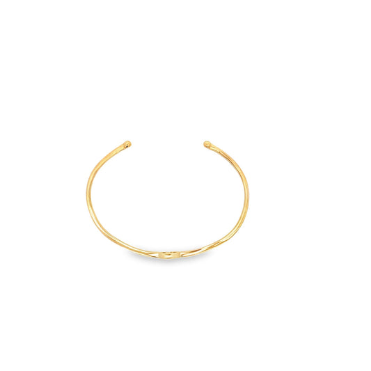 A minimalist gold cuff bracelet rests on a clean white background.