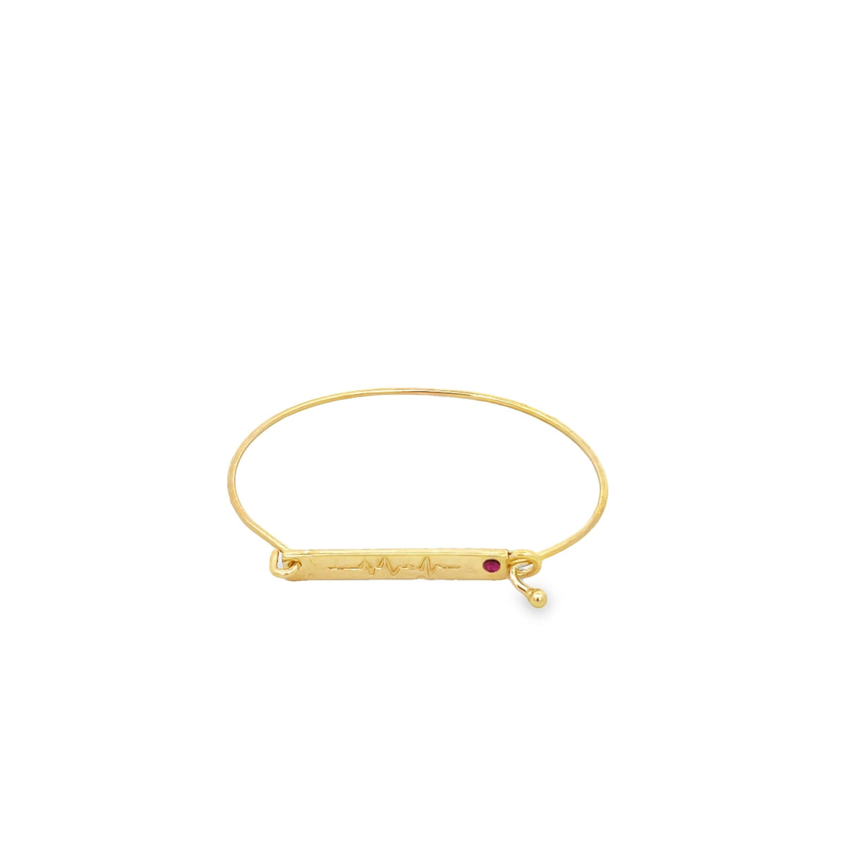A sleek gold bangle bracelet features an engraved EKG heartbeat line and a sparkling red gemstone accent on its central metal bar.