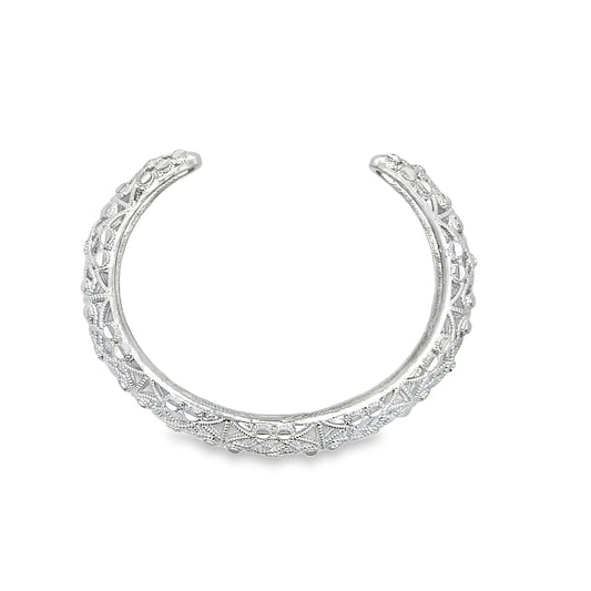 An intricate silver cuff bracelet with detailed filigree patterns rests against a clean white background.