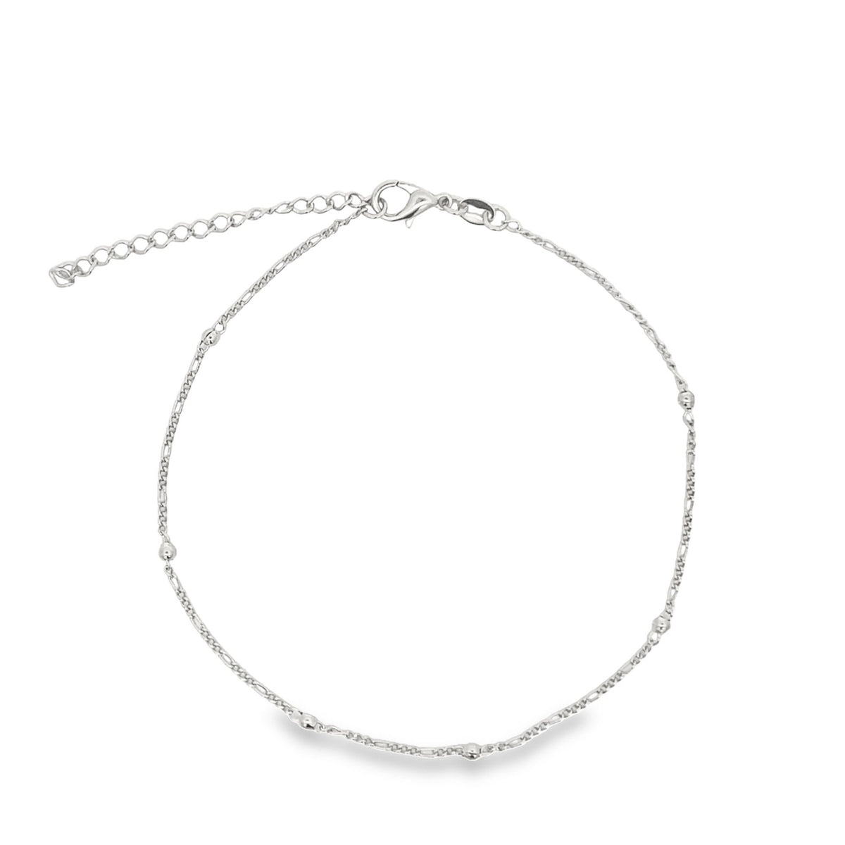A delicate silver anklet featuring a Figaro chain and small metallic beads rests on a clean white background.