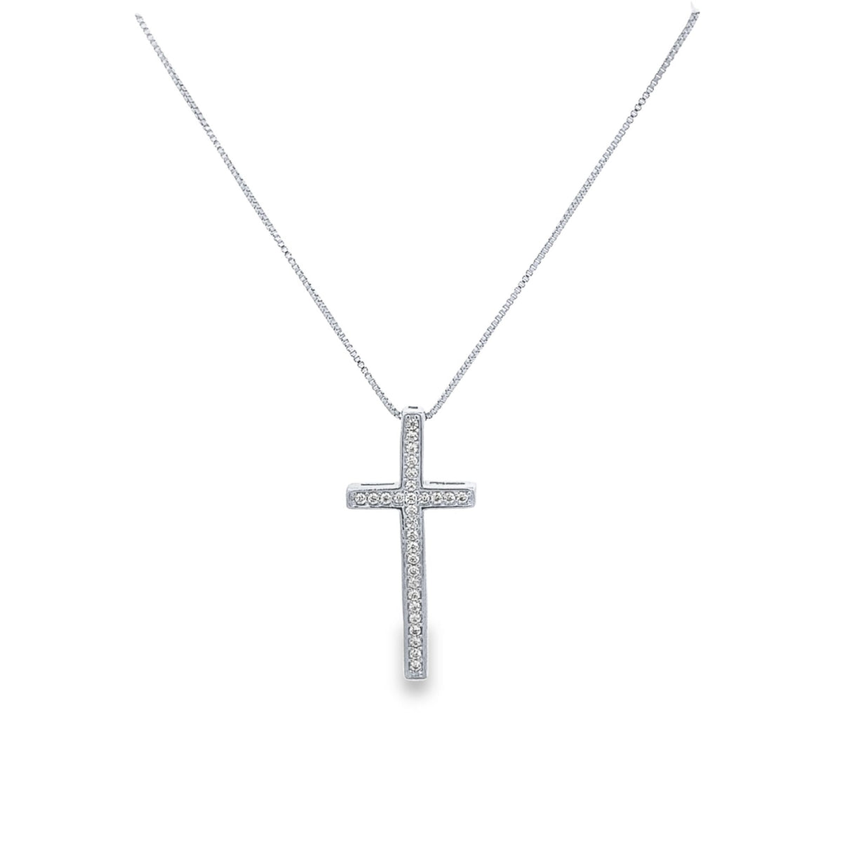 A delicate silver cross pendant embellished with sparkling diamonds hangs from a matching box chain against a white background.