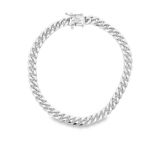 A polished silver Cuban link chain necklace rests in a circular shape with its clasp fastened at the top.