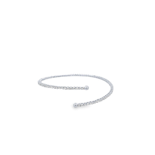 A delicate silver diamond tennis bracelet curves against a clean white background, showcasing a continuous line of sparkling stones ending in smooth metal spheres.