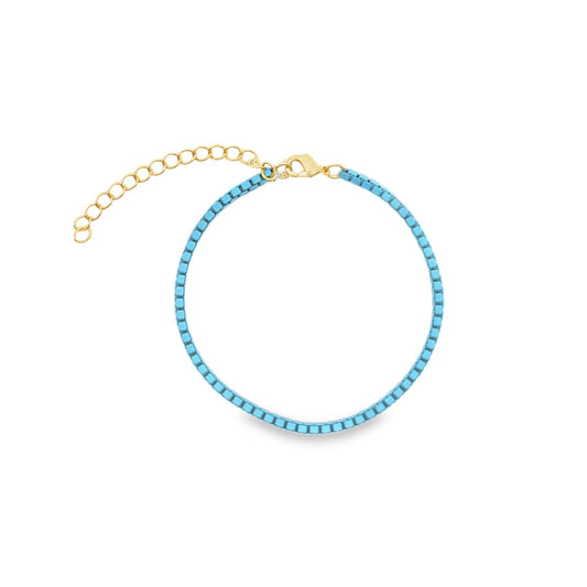 A delicate gold chain bracelet features vibrant turquoise square beads and an adjustable extender clasp.