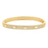 A gold bangle bracelet sparkles with pavé diamonds and features five evenly spaced baguette-cut stones.