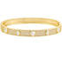 A gold hinged bangle bracelet sparkles with pavé-set crystals and alternates between heart and oval gemstones.