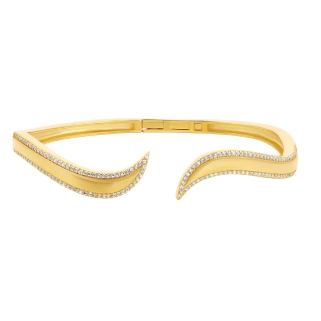 A gold cuff bracelet sparkles with pavé diamonds along its wavy, open-ended design.
