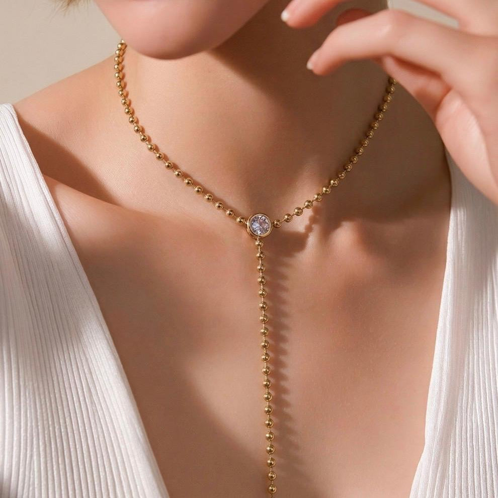 Elegant beaded lariat necklace with bezel-set stone and drop chain. Minimalist Y necklace available in gold or silver. Perfect for everyday wear or layering.