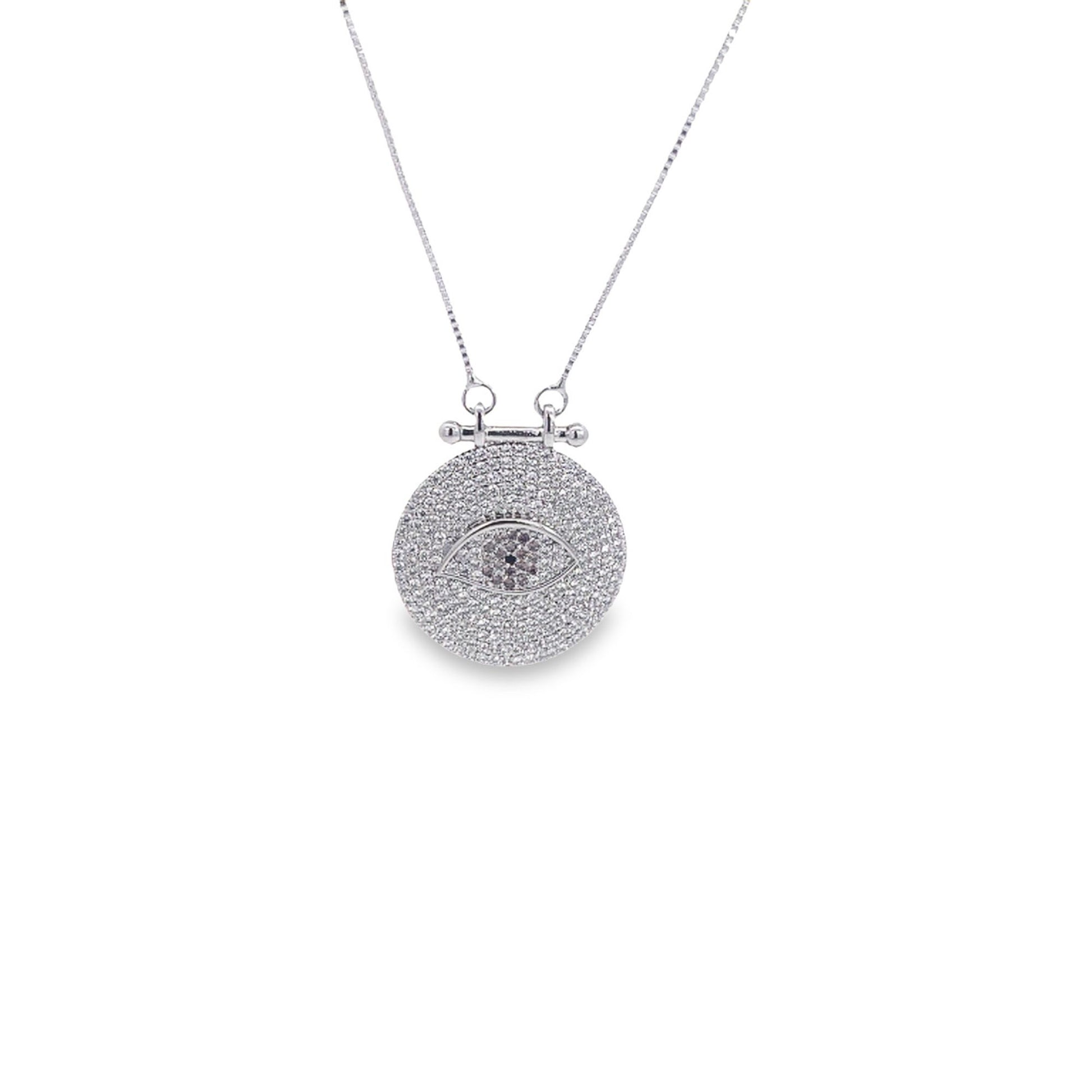 A sparkling silver pendant necklace features a round medallion encrusted with cubic zirconia stones forming an intricate evil eye design.