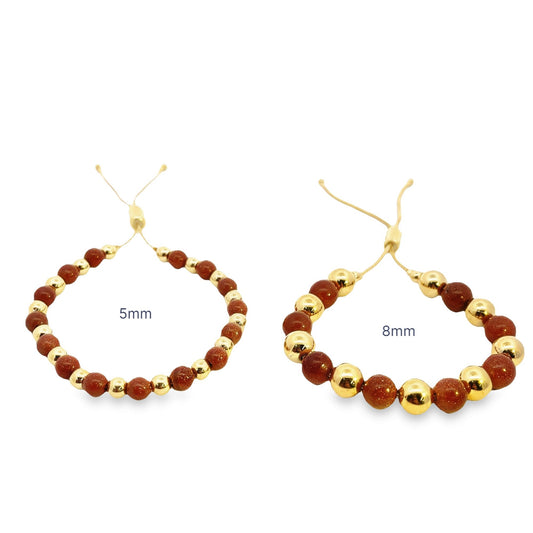 Two adjustable goldstone and gold bead bracelets, featuring 5mm and 8mm stone sizes respectively, rest against a clean white background.