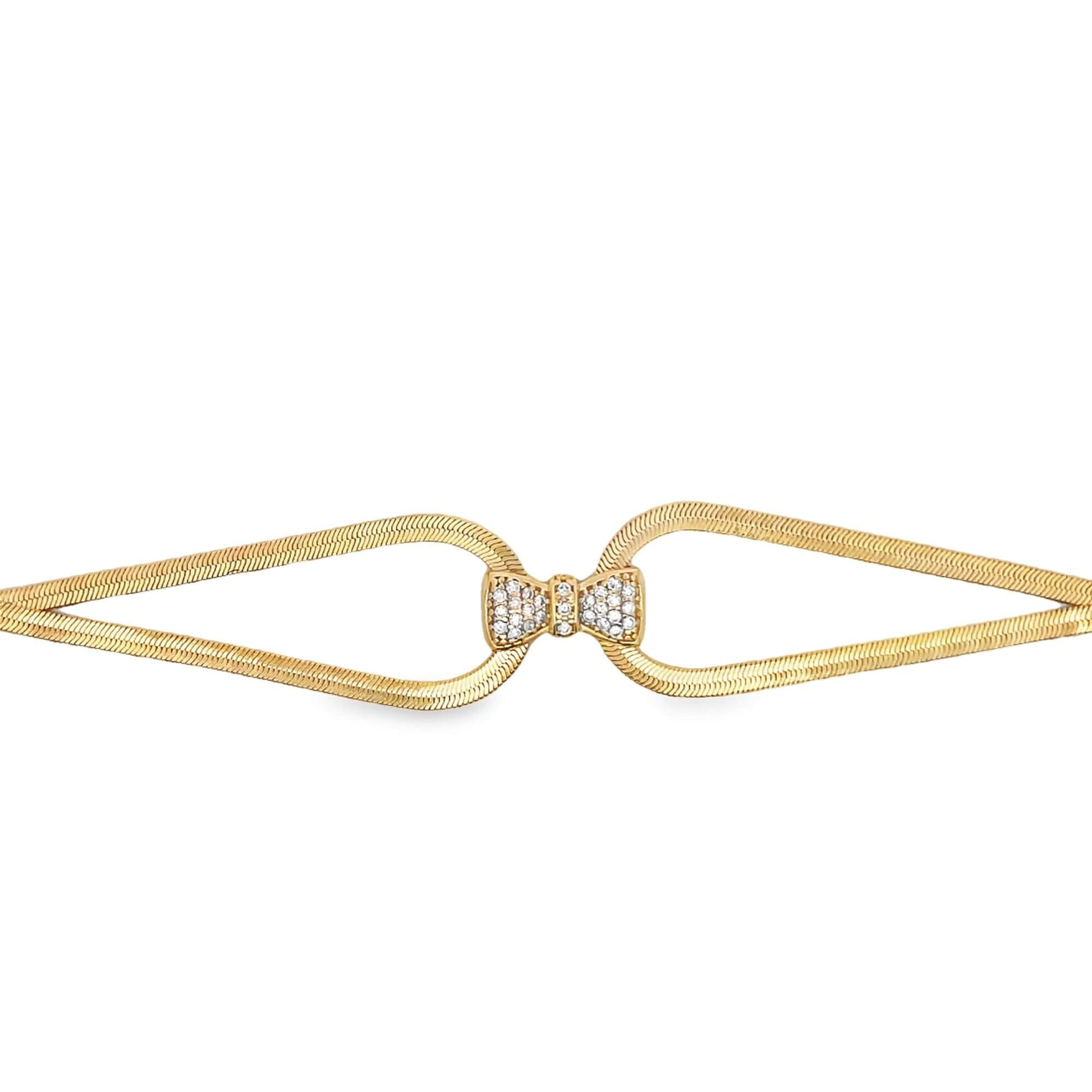 A gold herringbone chain bracelet features a sparkling diamond-encrusted bow clasp at the center.