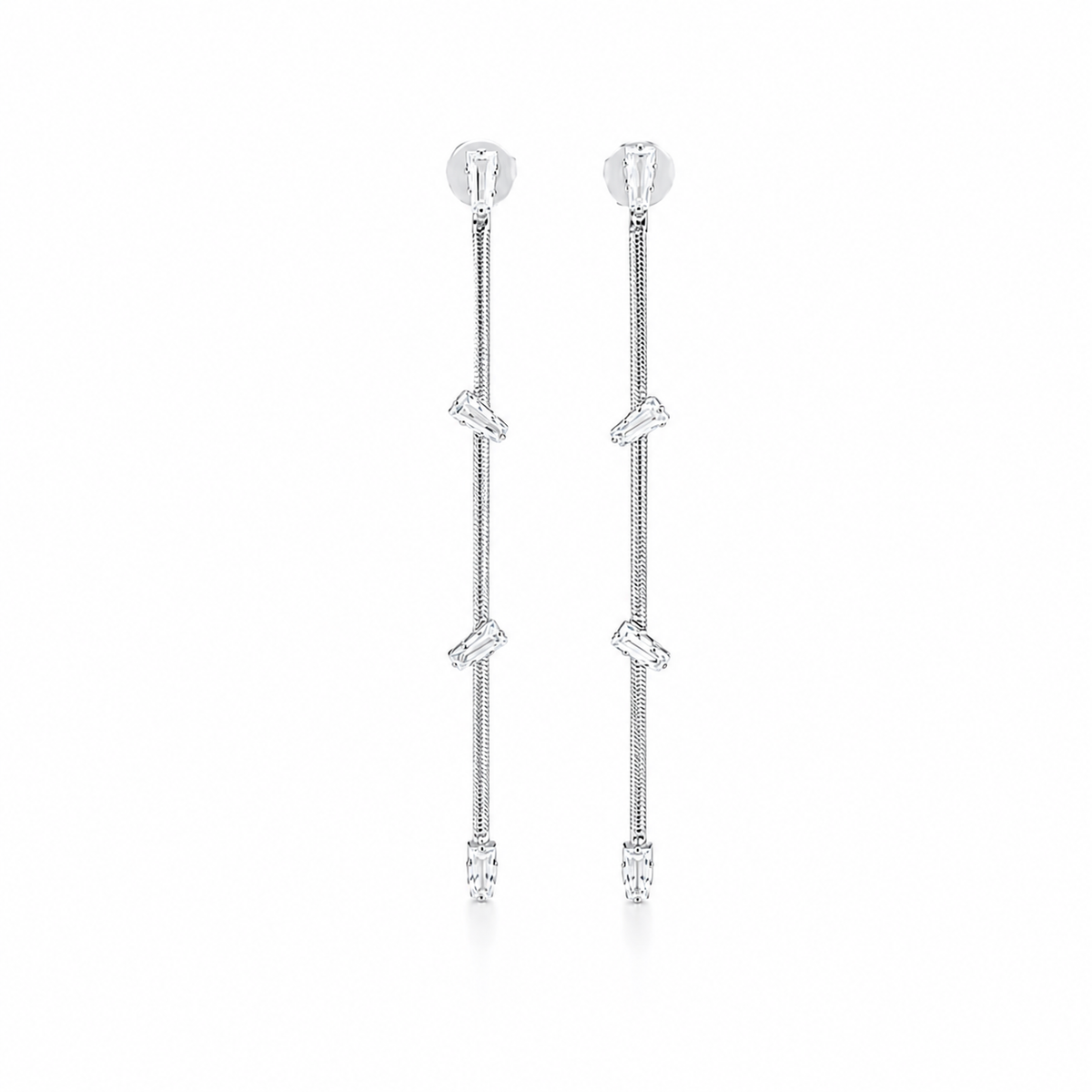 A pair of sleek silver chain drop earrings sparkles with dangling baguette-cut diamond accents against a clean white background.