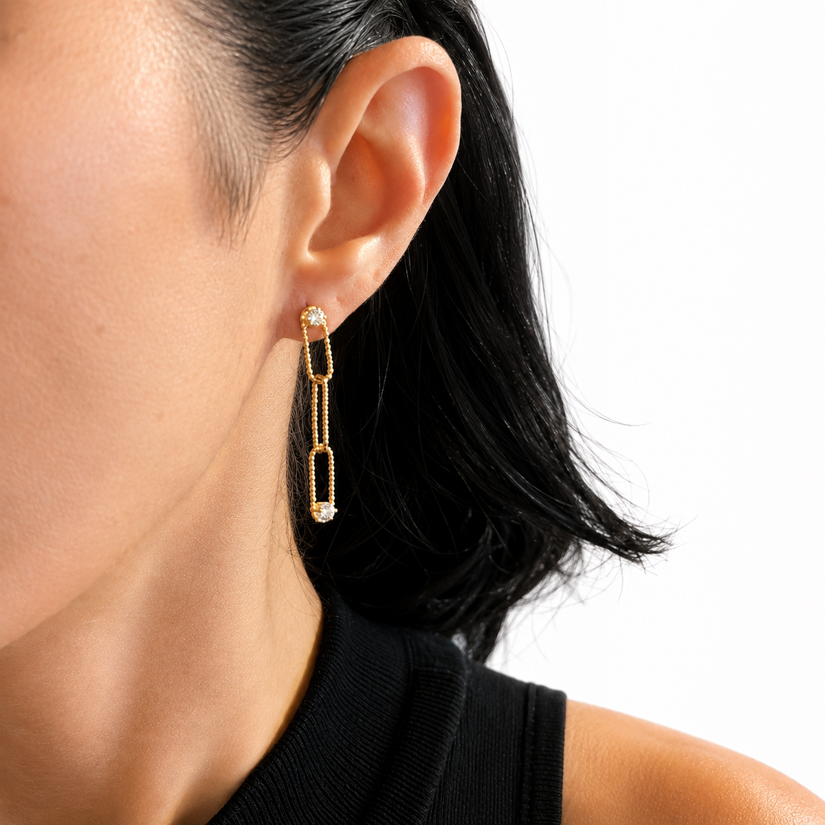 A woman with dark hair wears an elegant gold link drop earring featuring delicate diamond studs.