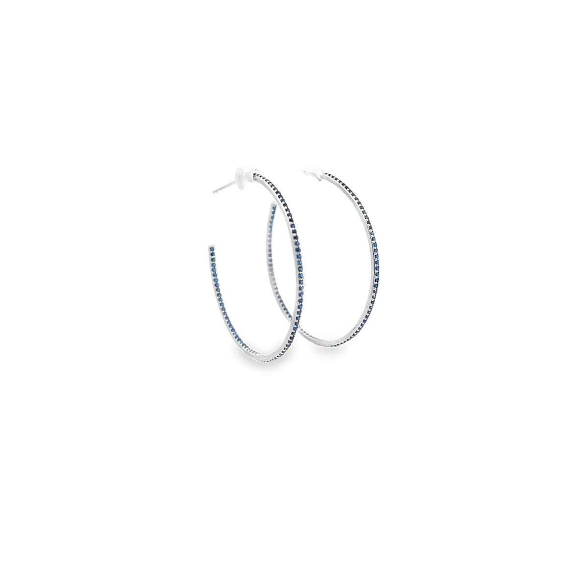 A pair of silver hoop earrings studded with tiny blue sapphire gemstones rests against a clean white background.