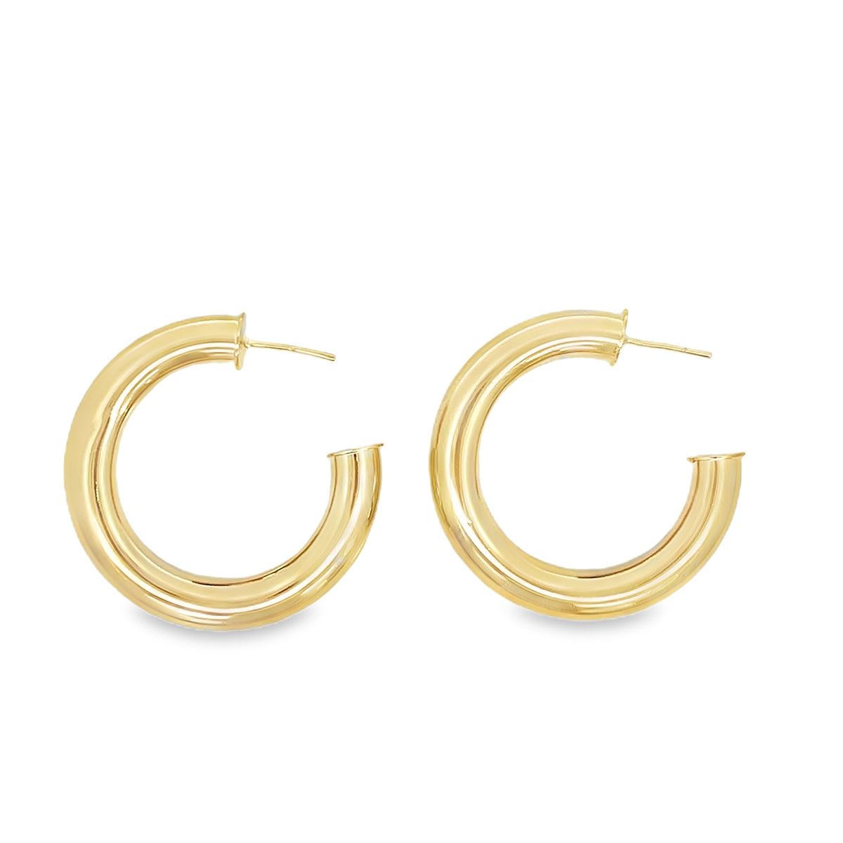 A pair of thick, polished gold hoop earrings rests against a clean white background.