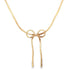 A delicate gold herringbone chain necklace features a stylish bow pendant hanging against a plain white background.