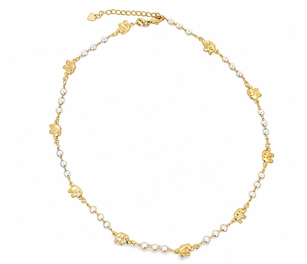 A gold necklace features alternating white pearls and miniature gold elephant charms arranged in a circle against a white background.