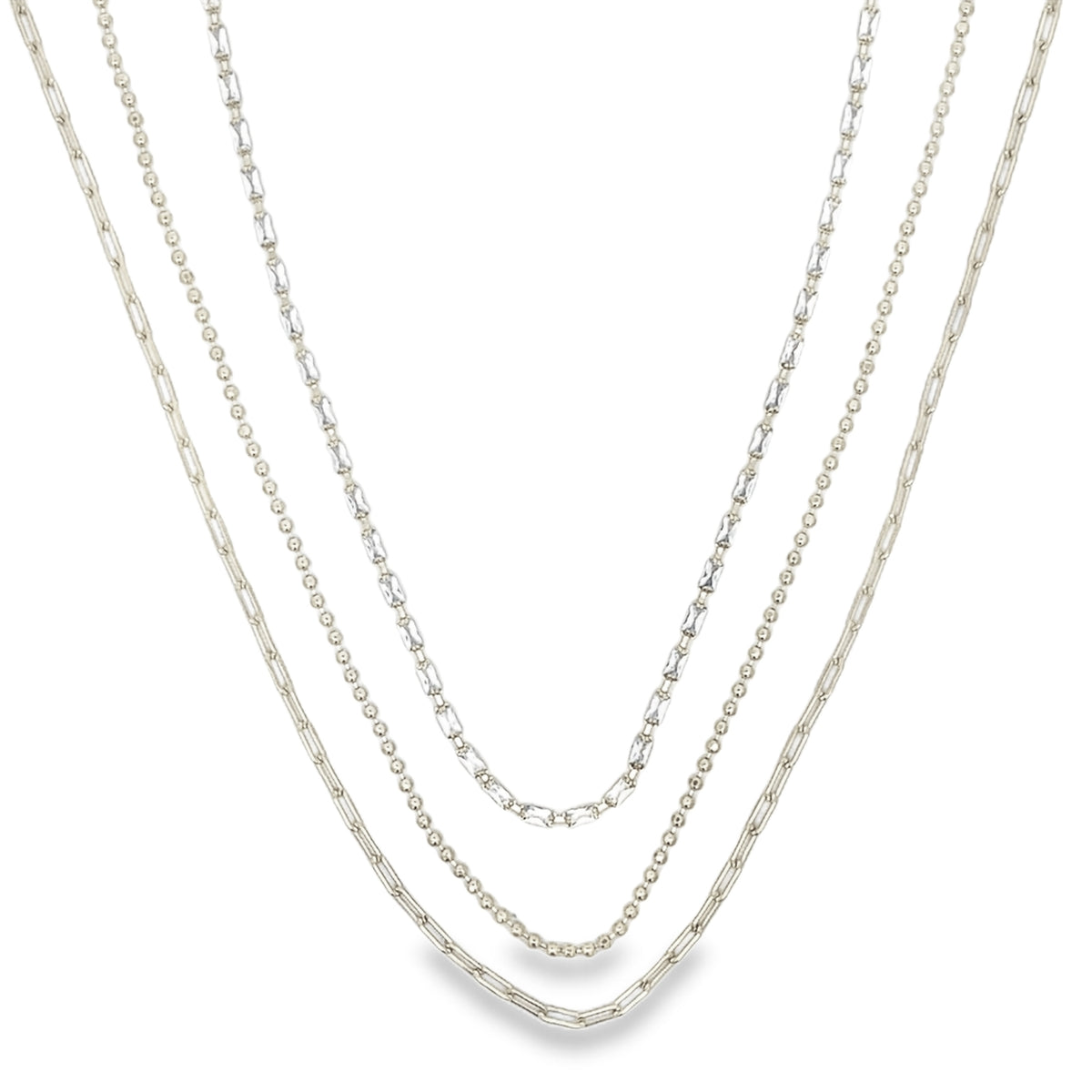 A trio of layered silver necklaces features delicate paperclip links, tiny beads, and sparkling crystal accents against a plain white background.