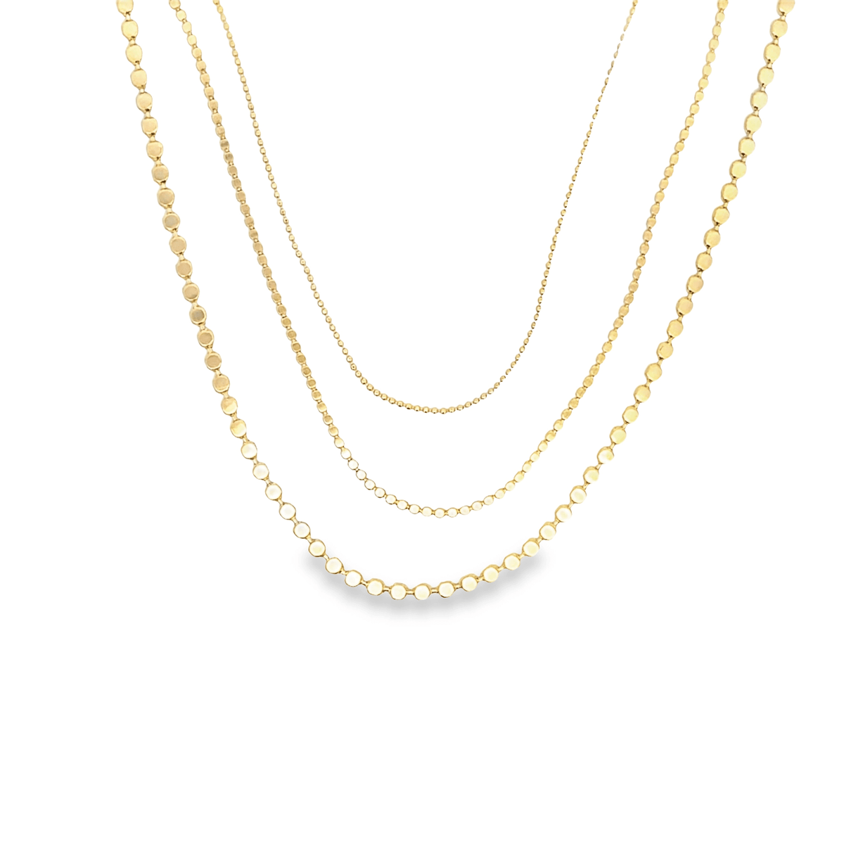 Three delicate gold chain necklaces with varying bead sizes drape gracefully in layered tiers against a clean white background.