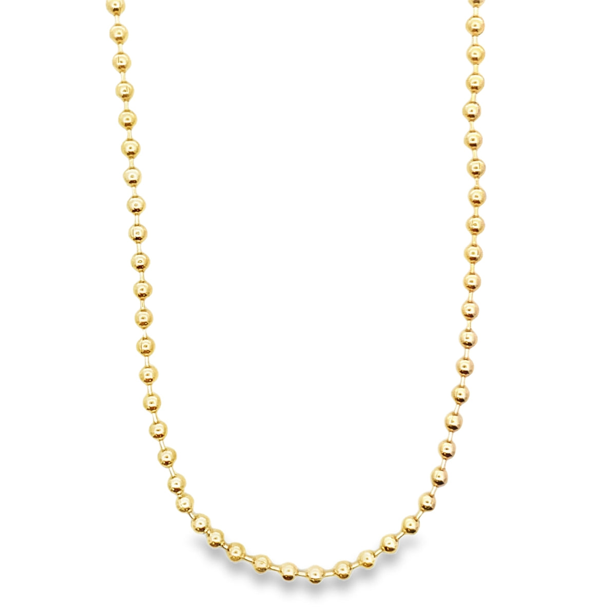 A delicate gold ball chain necklace hangs against a white background.