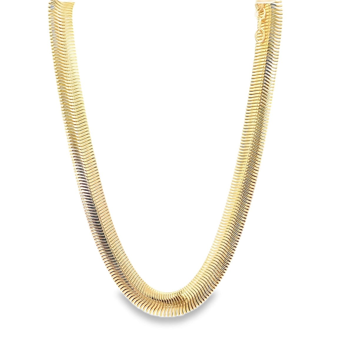 A wide, flat gold herringbone chain necklace curves gracefully against a clean white background.