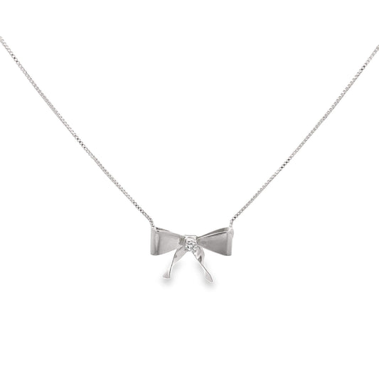 A delicate silver bow necklace features a sparkling diamond at its center against a clean white background.