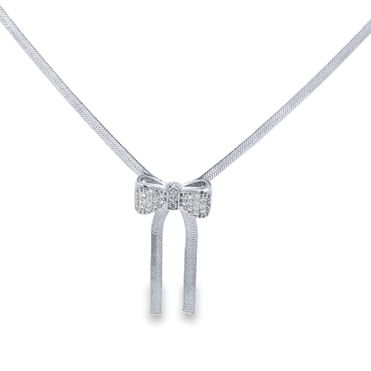A delicate silver necklace features a sparkling bow pendant encrusted with tiny gemstones and hanging ribbons.