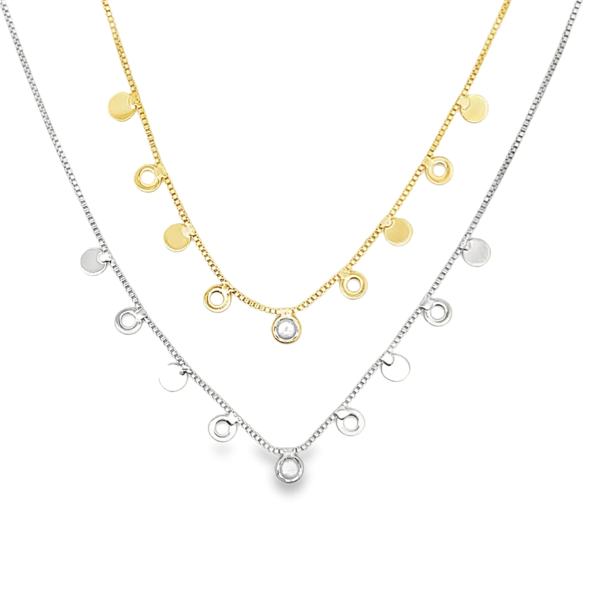 A gold necklace with coin charms and a silver necklace with charm drops are layered together against a white background.