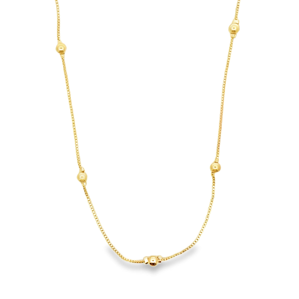 A delicate gold box chain necklace features evenly spaced small golden beads against a white background.