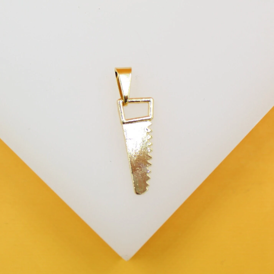A shiny gold pendant in the shape of a hand saw rests against a white and yellow background.