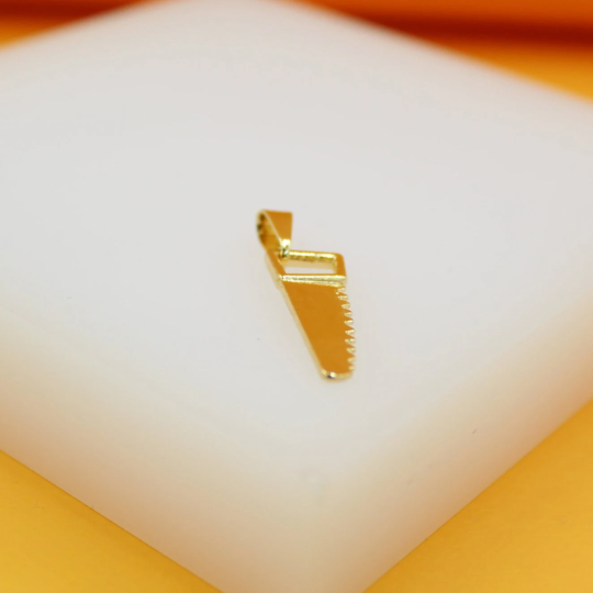 A shiny gold saw pendant rests on a clean white display block.